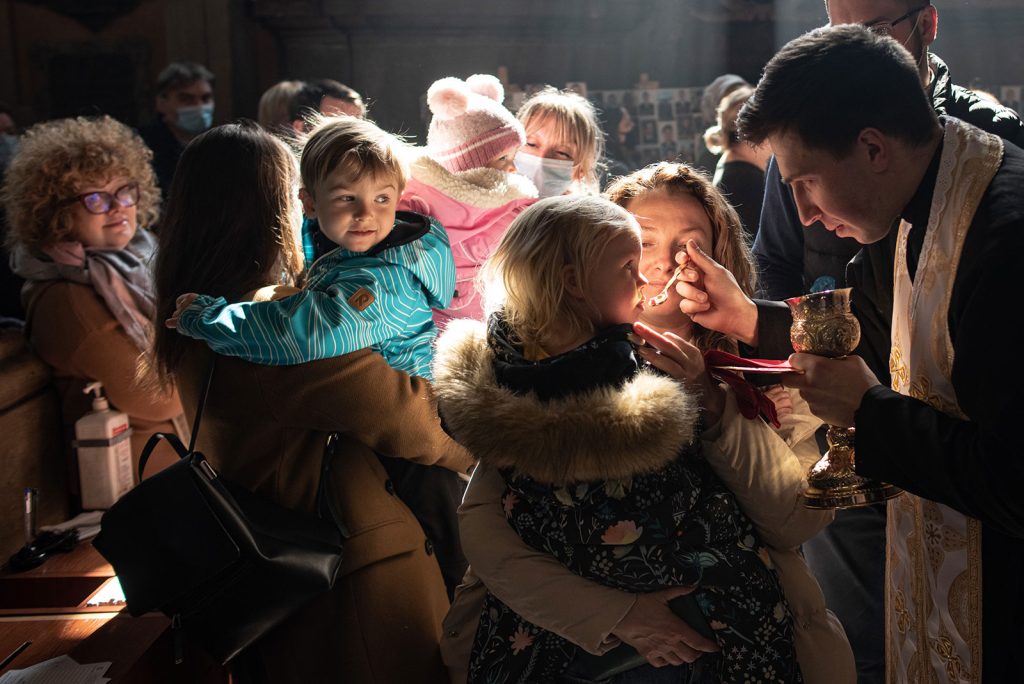 A girl receives communion during a church service at Saints Peter and Paul Garrison Church on Sunday, March 20 in Lviv, Ukraine. The city has served as a stopover and shelter for the millions of Ukrainians fleeing the Russian invasion.