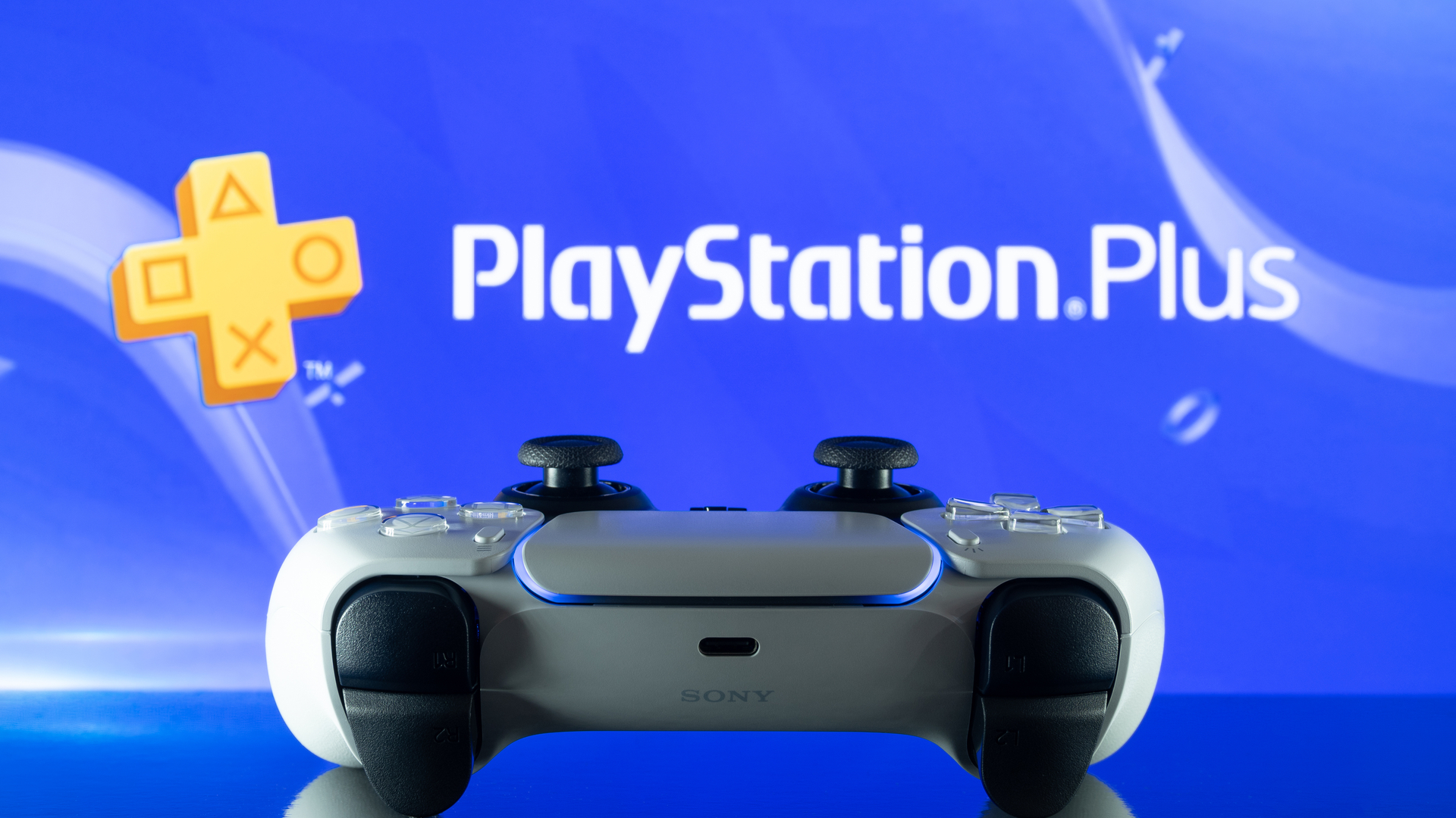 Controller DualSense PS5 davanti al logo PlayStation Plus