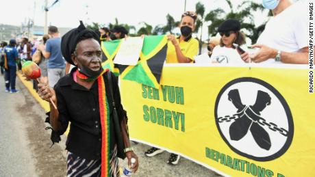 Martedì le persone chiedono risarcimenti per la schiavitù fuori dall'ingresso dell'Alto Commissariato britannico a Kingston, in Giamaica.