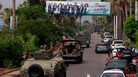 I veicoli dell'esercito libanese passano davanti a un cartellone pubblicitario che raffigura i candidati alle elezioni del Parlamento di domenica a Beirut, in Libano, il 14 maggio.