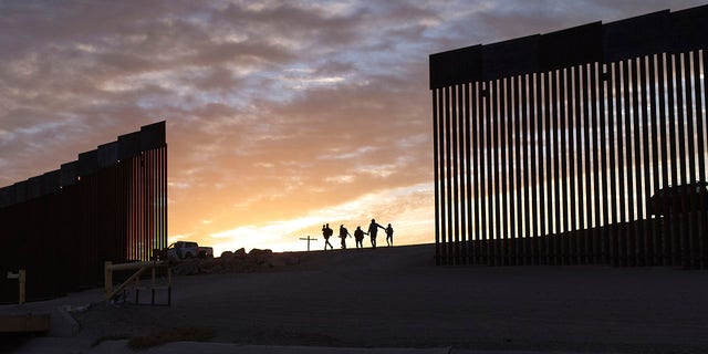 FILE - Famiglie di immigrati provenienti dal Brasile attraversano un varco nel muro di confine per raggiungere gli Stati Uniti dopo aver attraversato dal Messico a Yuma, in Arizona, per chiedere asilo.
