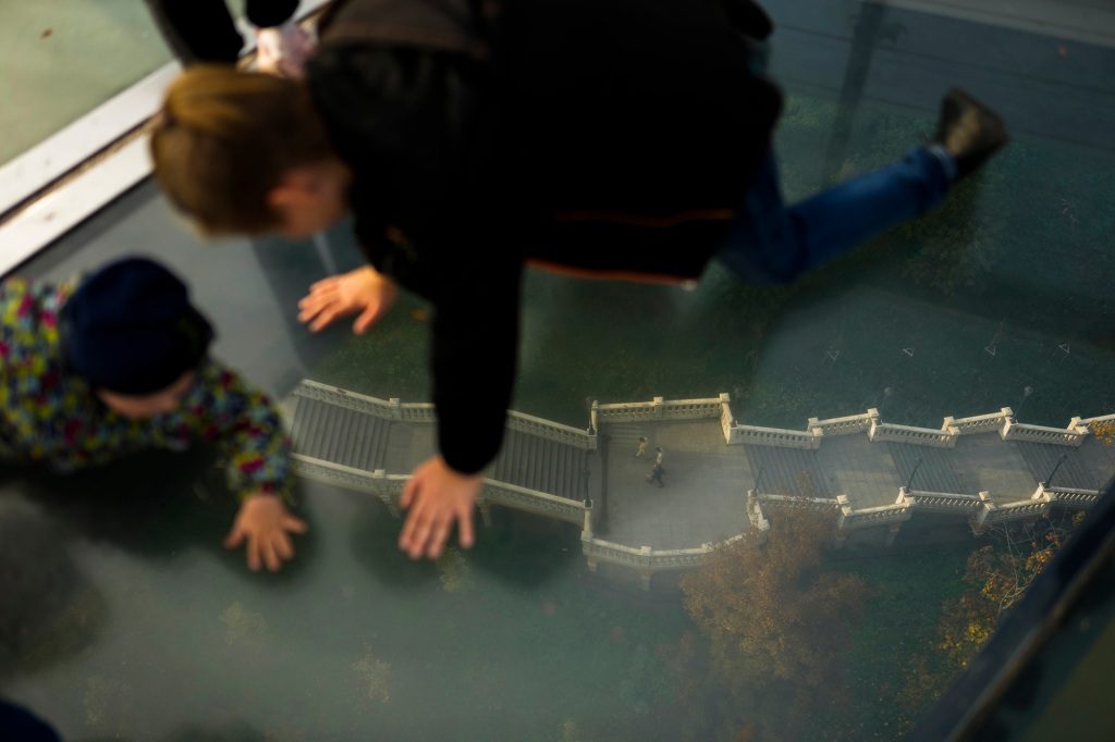 Due bambini che guardano attraverso il pavimento di vetro del ponte
