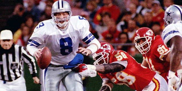 Il quarterback dei Dallas Cowboys Troy Aikman sta per essere licenziato dal quarterback dei Kansas City Chiefs Derek Thomas (a destra) a Kansas City.