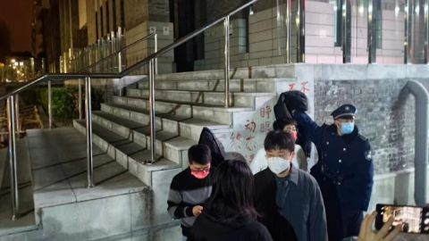 Una guardia di sicurezza cerca di coprire uno striscione di protesta contro Zero Covid nel campus dell'Università di Pechino a Pechino.