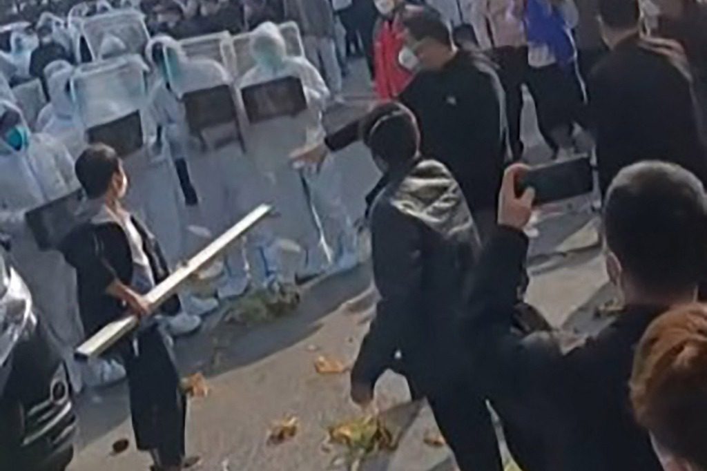 Un uomo con un lungo palo affronta la polizia in Cina