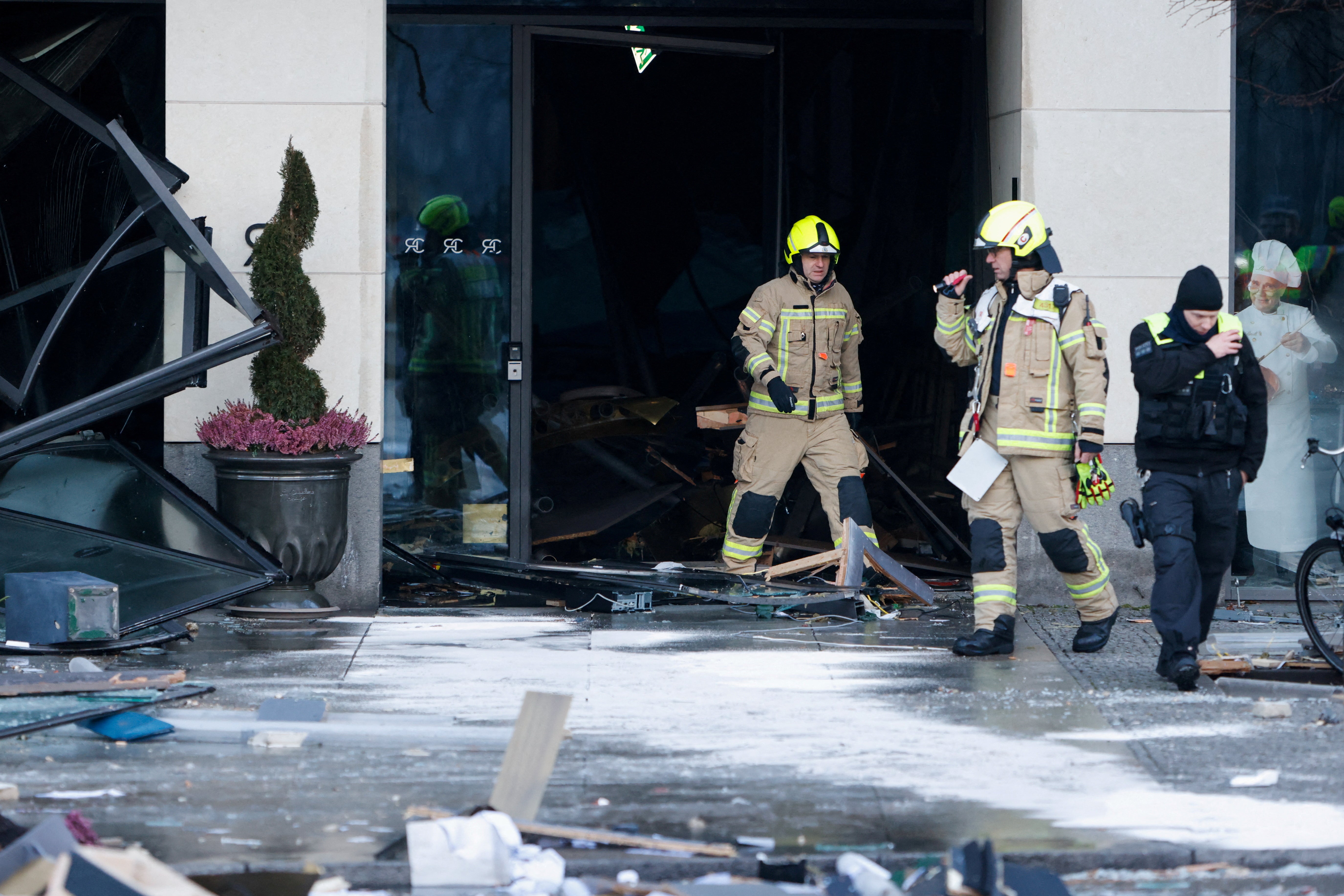 I soccorritori sono fuori da un edificio, con molti vetri rotti e detriti intorno a loro.